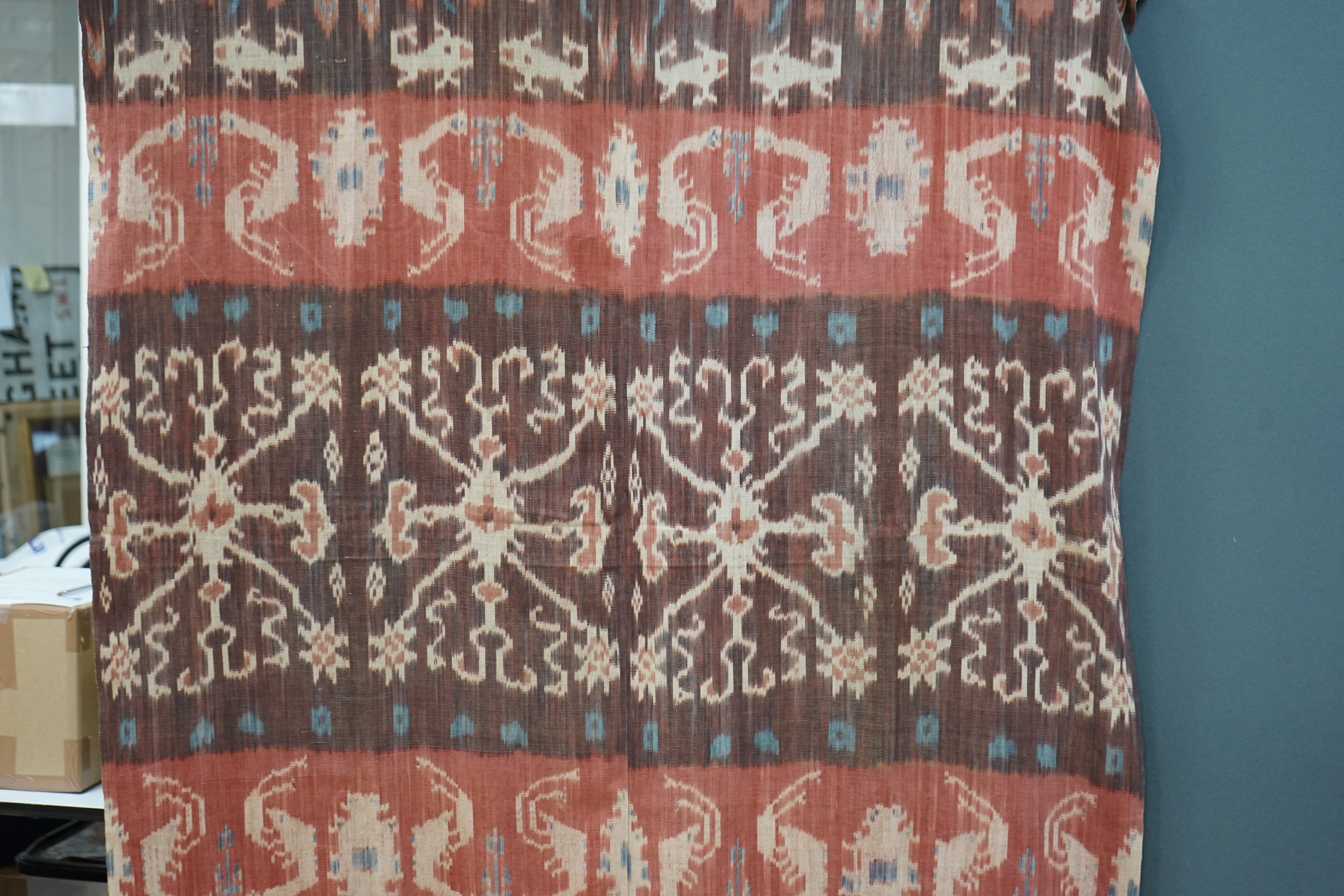 A hand woven hand dyed Ikat Sumbanese Hinggi (shoulder cloth), together with an Indian chain stitch embroidered panel, the Hinggi woven on two short 56cm wide looms sewn together forming horizontal bands, depicting men o